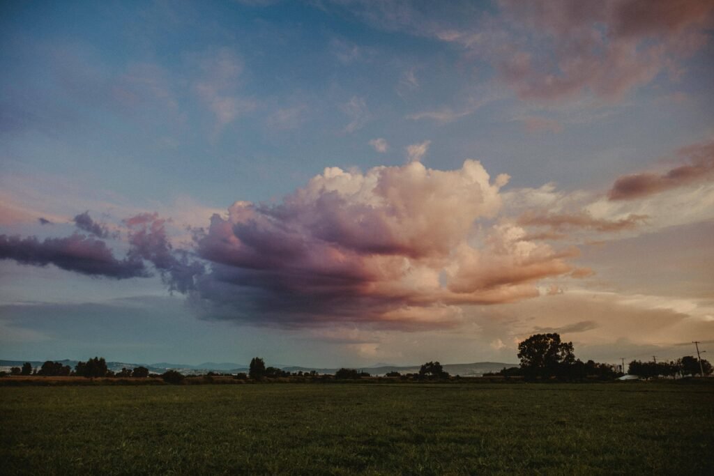 storm a large green field with trees and clouds