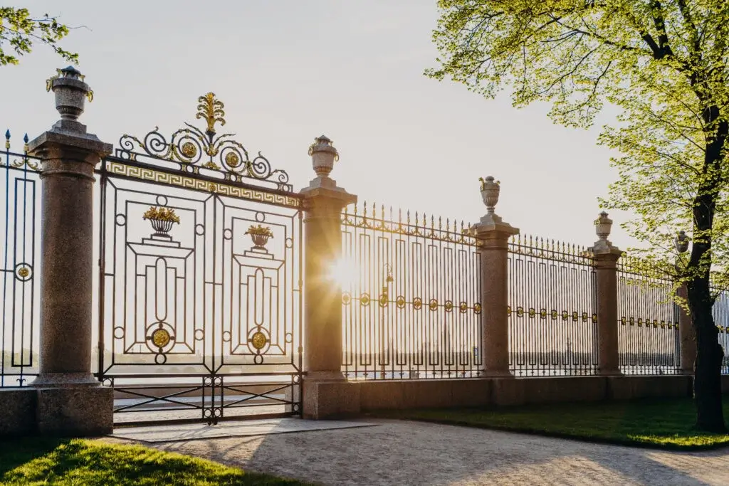 Gates of Summer Garden in Russia, Saint Petersburg. Sunny spring day. Green beautiful trees and grass. Fence with gate. Masterpiece of architecture