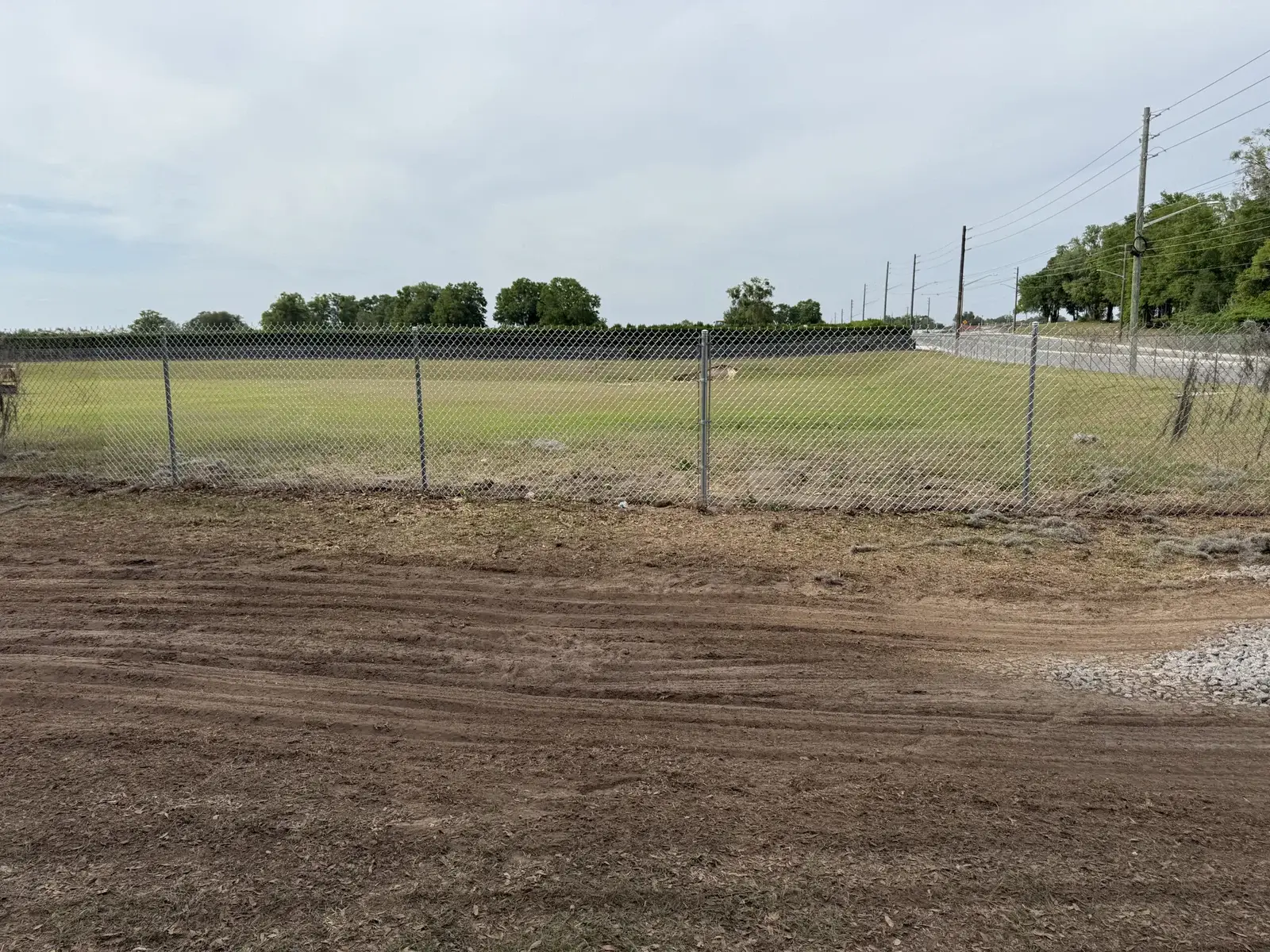 Commercial chain link fence enclosing a cleared field, showcasing Bell's Outdoor Services' fencing project in Florida.