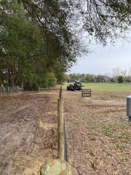 Newly constructed perimeter fence line with a vehicle preparing the field, showcasing Bell's Outdoor Services' fencing and land clearing expertise in Florida.