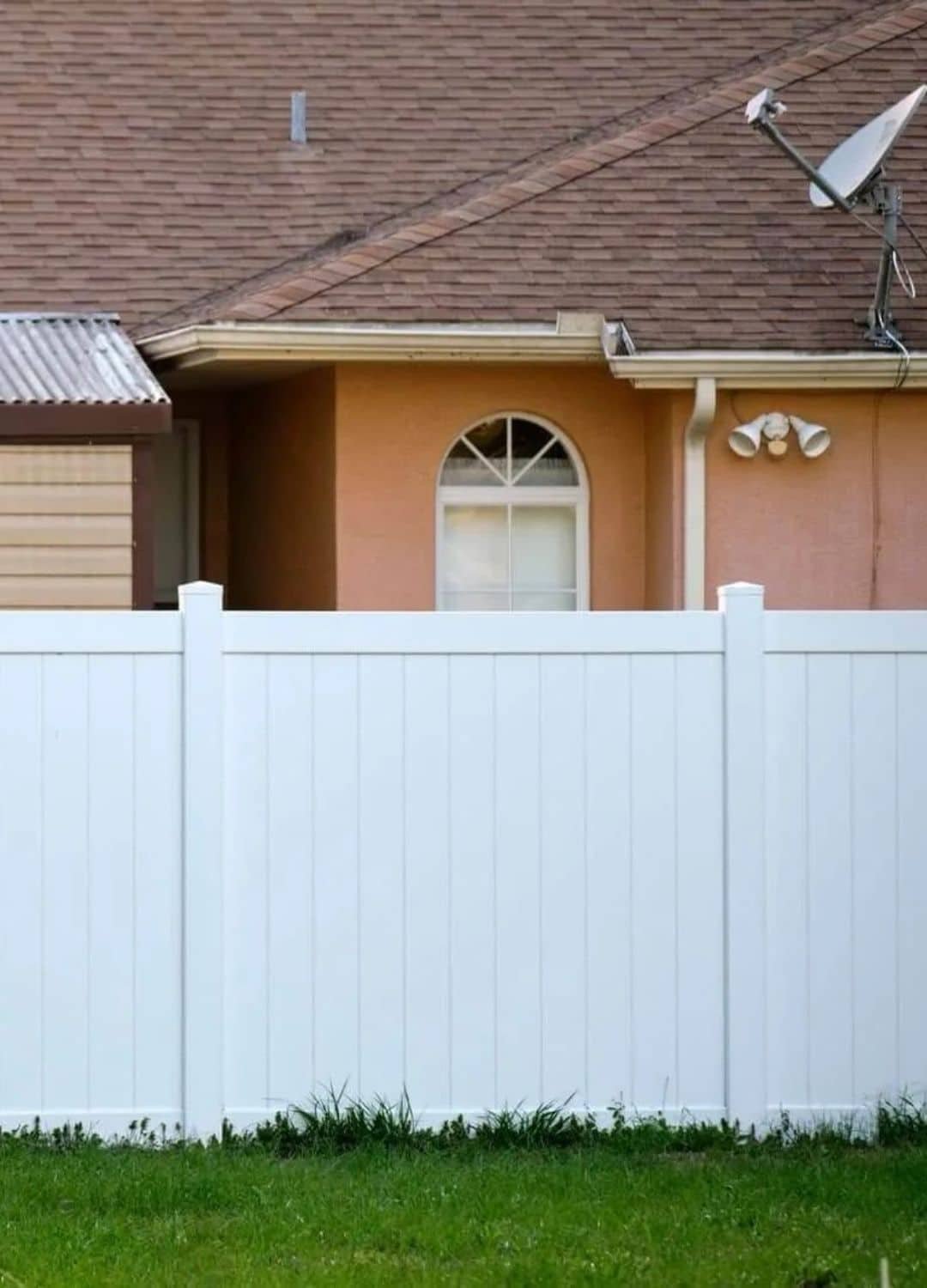 A newly installed white vinyl privacy fence in a residential backyard, providing a clean and secure boundary.